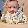 baby, high_chair, bib, straps, indoor, kitchen, fridge, face, expression, child, clothing, seat, person, young, cute, pout, sitting, infant, home, portrait