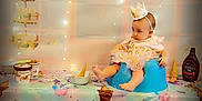 Luna'Rae is registered to the contest to win money with this photo: baby, child, crown, blue_seat, pink_dress, tablecloth, ice_cream_cone, ice_cream_tub, hersheys_syrup, string_lights, party, birthday, decorations, cupcakes, bowl, food, colorful, indoor, celebration, cute