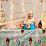 Luna'Rae is registered to the contest to win money with this photo: baby, child, crown, pink_dress, blue_seat, tablecloth, ice_cream, cone, bowl, spoon, chocolate_syrup, fairy_lights, party, celebration, smiling, indoor, pastel_colors, decorations, happy, portrait