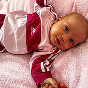 Maïvy participe au concours pour gagner de l'argent avec cette photo : baby, infant, child, pink_blanket, adidas_clothing, sporty_outfit, lying_down, cute, portrait, face, hand, soft_texture, relaxed, indoor, closeup, smiling, young_child, casual_wear, comfortable, resting