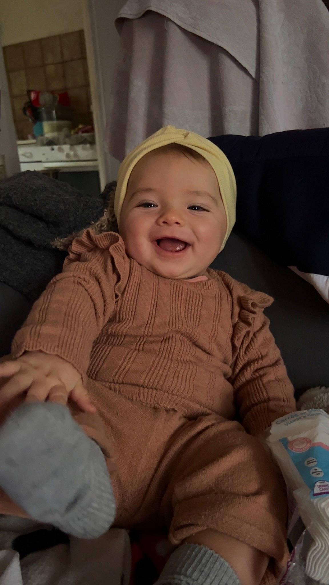 Nina a rejoint le concours — aidez-le/la à gagner de superbes lots ! baby, baby_toddler_clothing, cheek, child, comfort, couch, facial_expression, foot, fun, happy, human_body, joy, lap, laugh, person, room, sitting, skin, sleeve, smile