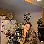 Edana joined the competition — help win amazing prizes! woman, cat, kitchen, tattoos, glass, straw, counter, refrigerator, papers, spider_web, plaid_shirt, gray_cat, drink, sink, water_bottle, decor, indoor, casual, relaxed, home