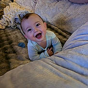 Jaxxon is registered to the contest to win money with this photo: baby, bed, bedding, blanket, brown_hair, child, couch, cozy, face, happy, home, indoors, infant, lifestyle, onesie, pacifier, portrait, sitting, smiling, striped_clothing