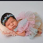 Nyla joined the competition — help win amazing prizes! baby, newborn, sleeping, infant, dress, headband, flower, pastel_colors, frills, pillow, soft, peaceful, cute, portrait, resting, child, indoors, closeup, adorable, sleep