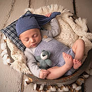 Diego participe au concours pour gagner de l'argent avec cette photo : baby, sleeping, hat, knitwear, blanket, teddy_bear, wooden_floor, cotton, cozy, infant, cute, peaceful, small, resting, portrait, indoor, soft_lighting, child, relaxing, circular_bowl