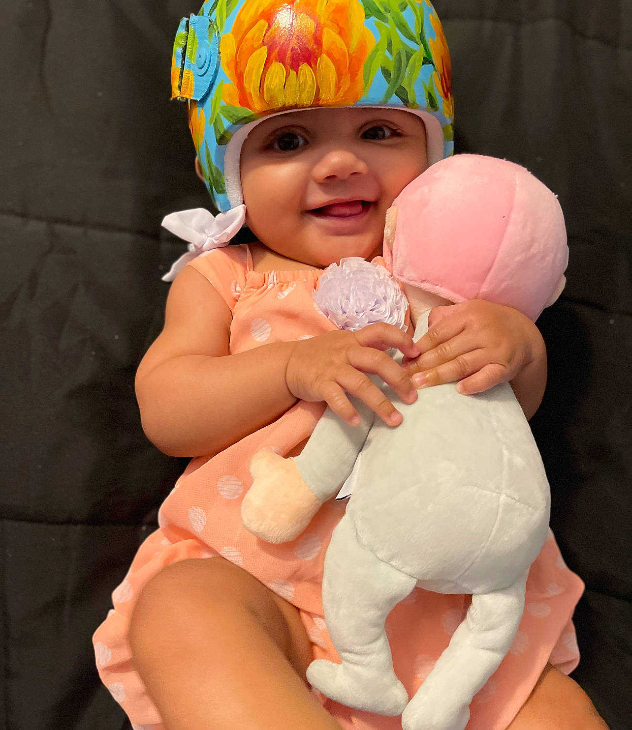 Avani is registered to the contest to win money with this photo: baby, baby_toddler_clothing, cap, child, face, facial_expression, finger, fun, gesture, happy, hat, head, headgear, headwear, helmet, joy, party_supply, person, pink, smile