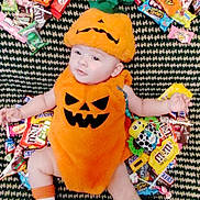 Penelope joined the competition — help win amazing prizes! baby, pumpkin_costume, halloween, candy, carpet, toy, sock, cute, infant, orange, green, pattern, lying_down, holiday, festive, smile, face, child, costume, celebration