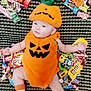 baby, pumpkin_costume, halloween, candy, carpet, toy, sock, cute, infant, orange, green, pattern, lying_down, holiday, festive, smile, face, child, costume, celebration