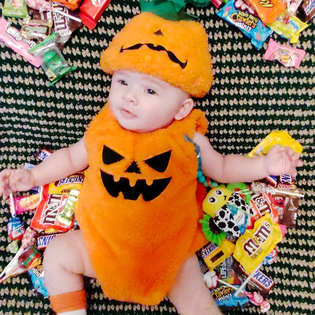 Penelope joined the competition — help win amazing prizes! baby, candy, carpet, celebration, child, costume, cute, face, festive, green, halloween, holiday, infant, lying_down, orange, pattern, pumpkin_costume, smile, sock, toy
