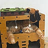 cat, orange_cat, wooden_cat_house, cat_toys, indoor, pet, stretching, fur, playful, cozy, floor, tile_floor, relaxed, cute, home, animal, whiskers, paws, feline, box