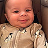 baby, infant, smile, face, penguin_pattern, onesie, clothing, cushion, seat, child, cute, happy, portrait, closeup, indoors, skin, head, young, baby_clothes, warm
