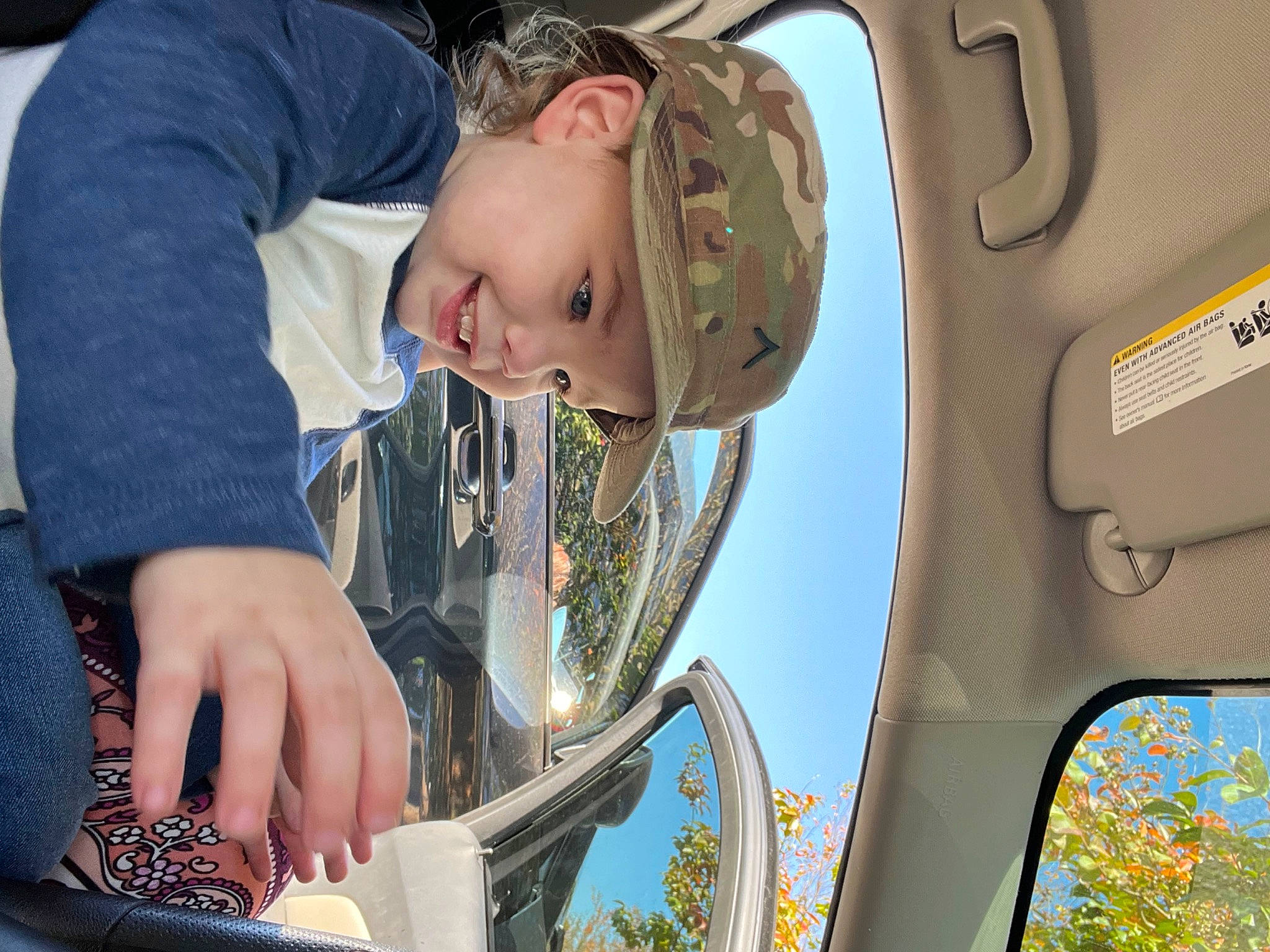 Carson is registered to the contest to win money with this photo: auto_part, automotive_design, automotive_exterior, automotive_lighting, automotive_mirror, car, clothing, fun, hair, happy, head, headwear, joy, mirror, motor_vehicle, person, sunglasses, tire, toddler, tree