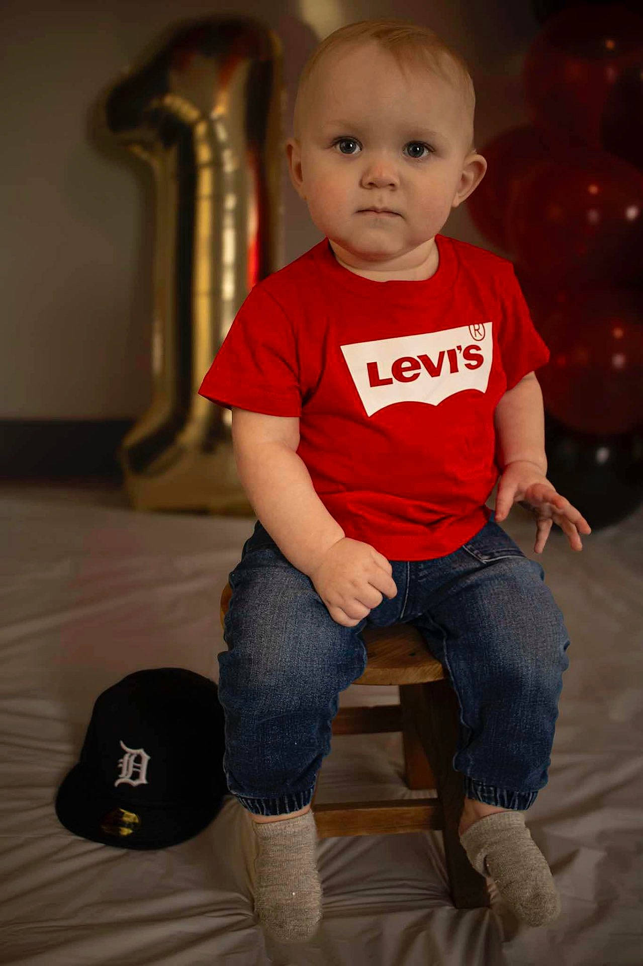 baby, baseballcap, clothing, couch, face, footwear, furniture, glove, hat, head, hosiery, jeans, pants, person, photography, portrait, shoe, sitting, sock, t_shirt