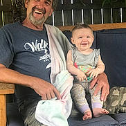 Harper joined the competition — help win amazing prizes! adult, baby, smiling, man, child, bench, cushion, blanket, casual_clothing, happy, portrait, indoor, wooden_furniture, family, holding, person, tshirt, camouflage, beard, blue_eyes