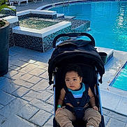 Edgar joined the competition — help win amazing prizes! toddler, child, stroller, pool, outdoor, water, pavement, building, plants, shoes, clothing, sunlight, handrail, residential, relaxing, daytime, sitting, person, urban, casual