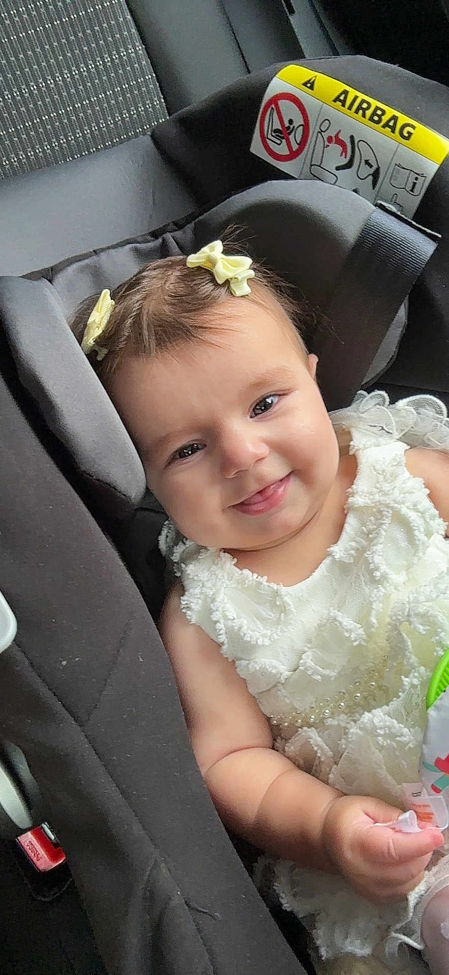 Pelin joined the competition — help win amazing prizes! baby, car_interior, car_seat, child, closeup, cute, dress, hair_bow, happy, holding, indoor, infant, portrait, safety_label, seat, seatbelt, smile, toy, white_dress, young_child