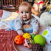 Paul participe au concours pour gagner de l'argent avec cette photo : baby, infant, toys, colorful_balls, quilt, floor, playtime, indoor, child, curious, soft_lighting, cushion, vacuum_cleaner, home, person, close_up, face, smiling, cute, toddler