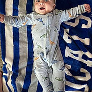 Nicholas joined the competition — help win amazing prizes! baby, infant, dinosaur_pajamas, blanket, blue, white, striped, smiling, happy, lying_down, feet, socks, carpet, child, cute, face, open_mouth, arms_outstretched, cozy, indoors