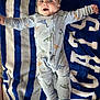 baby, infant, dinosaur_pajamas, blanket, blue, white, striped, smiling, happy, lying_down, feet, socks, carpet, child, cute, face, open_mouth, arms_outstretched, cozy, indoors