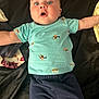 baby, blue_eyes, surprised_expression, light_blue_shirt, navy_pants, lying_down, blanket, infant, child, cute, arms_outstretched, indoor, clothing, soft_lighting, portrait, young_child, casual_wear, face, human, toddler
