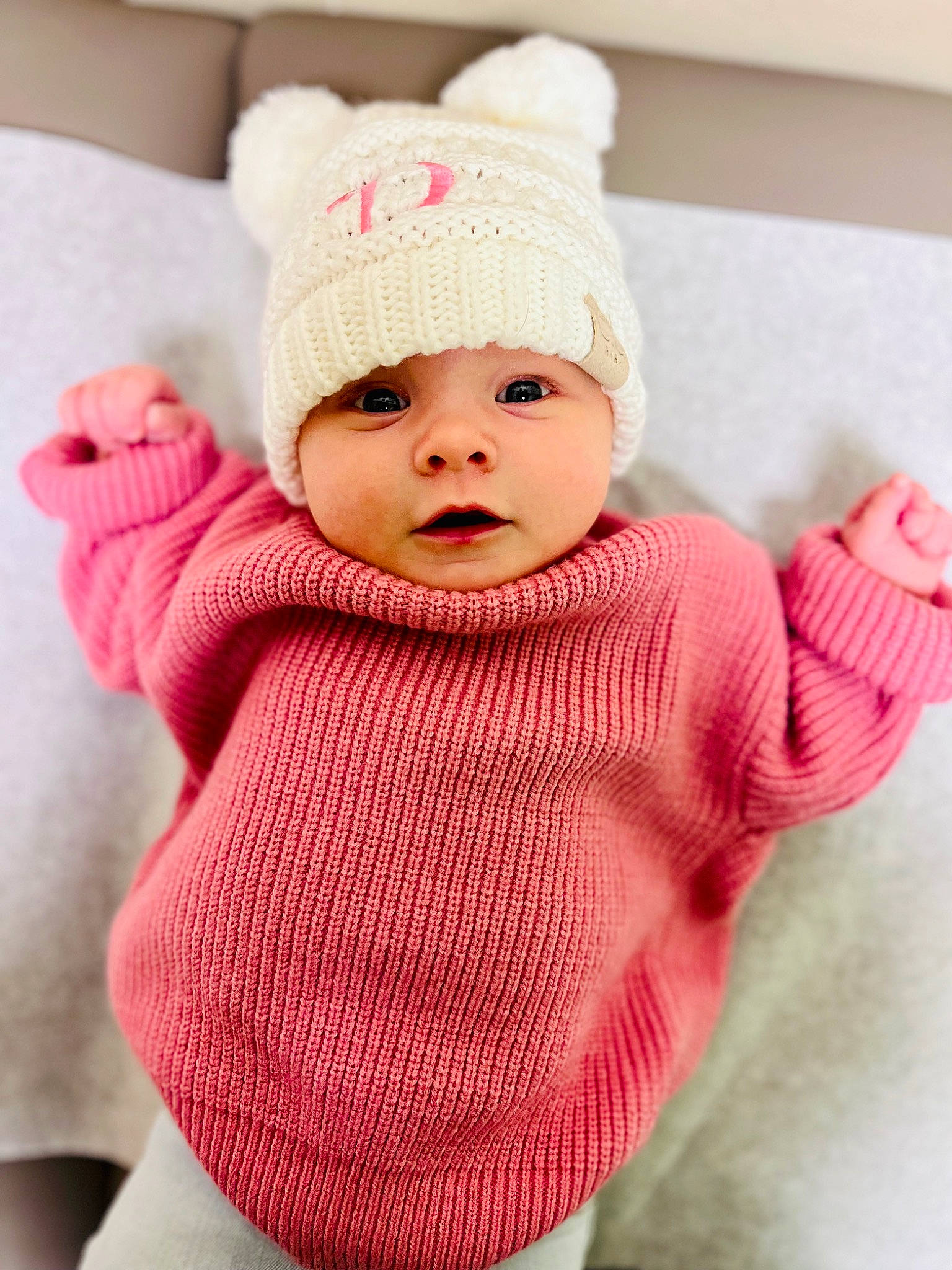 Zelda is registered to the contest to win money with this photo: baby, baby_toddler_clothing, cap, cheek, dress, eye, face, head, headgear, headwear, knit_cap, lip, outerwear, pattern, person, pink, product, skin, sleeve, textile