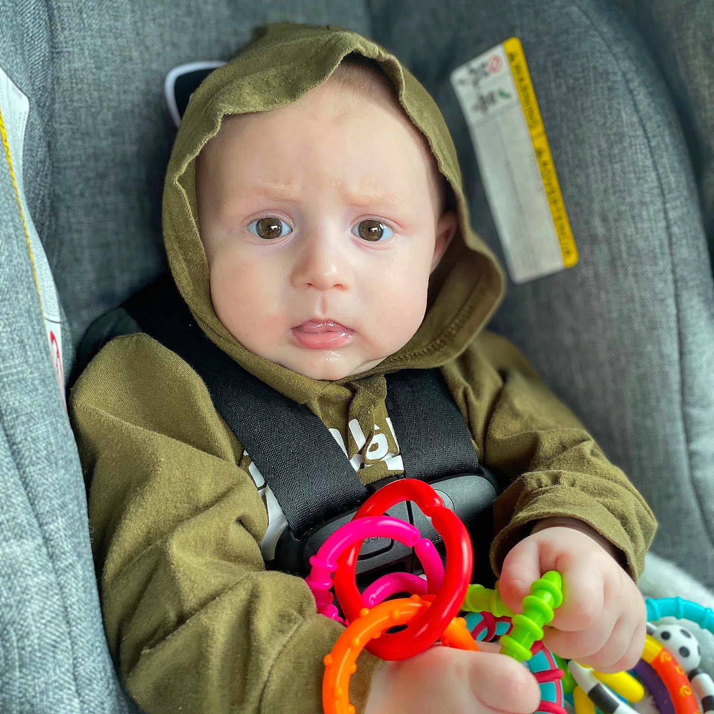 Ace is registered to the contest to win money with this photo: accessories, baby, bodypart, clothing, coat, couch, face, finger, furniture, hand, hat, head, jacket, knitwear, person, photography, portrait, rattle, sweater, toy