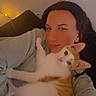 person, cat, indoor, couch, snuggling, cozy, relaxed, selfie, orange_and_white_cat, warm_lighting, casual_clothing, home, cute, pet, affection, morning, face, animal, comfort, love