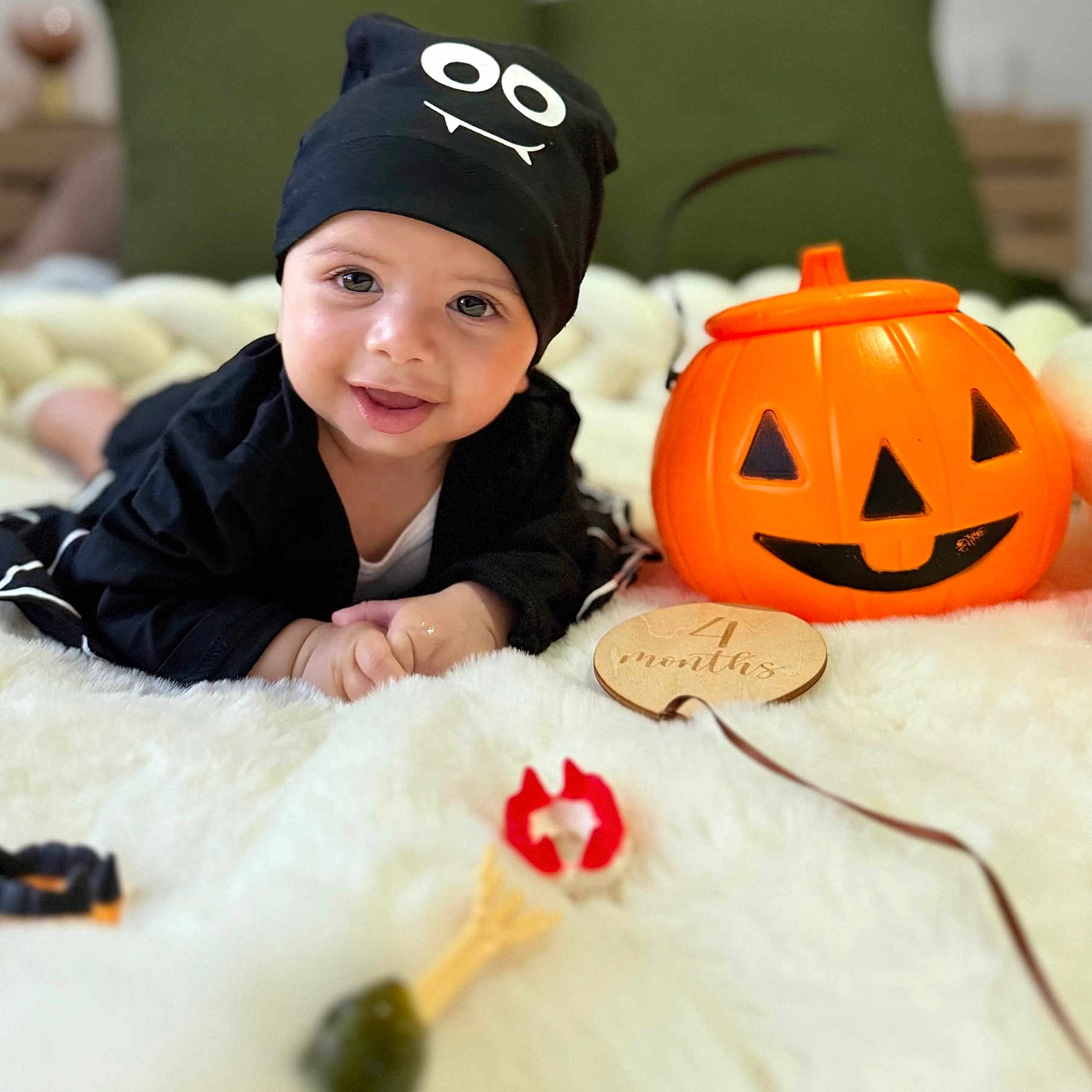 Ayane a rejoint le concours — aidez-le/la à gagner de superbes lots ! baby, black_clothing, child, cute, decor, face, happy, hat, holiday, indoor, infant, lying_down, milestone, orange, plush_blanket, portrait, pumpkin, smiling, toy, wooden_plaque