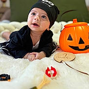 Ayane participe au concours pour gagner de l'argent avec cette photo : baby, infant, black_clothing, hat, pumpkin_bucket, wooden_plaque, 4_months, white_blanket, green_cushions, indoor, cute, portrait, child, lying_down, holiday, halloween, decor, face, expression, soft_focus