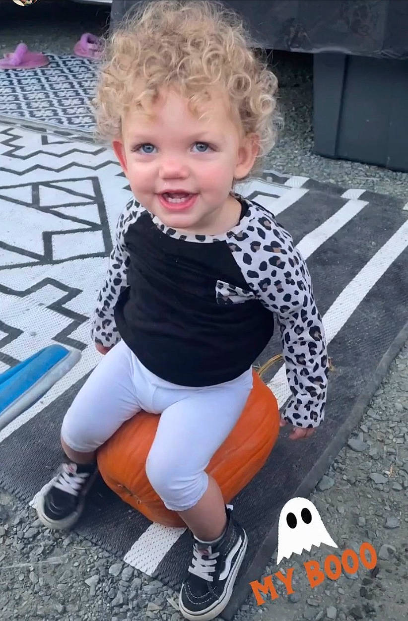 Lila is registered to the contest to win money with this photo: asphalt, baby, baby_toddler_clothing, child, electric_blue, flooring, fun, grass, happy, joy, pattern, person, photograph, recreation, road_surface, sitting, sleeve, smile, snapshot, sneakers