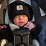 adorable, baby, black_beanie, car_seat, carhartt, child, closed_eyes, cozy, cute, indoor, infant, newborn, peaceful, portrait, safety, sitting, small_hands, straps, warm, winter_clothing