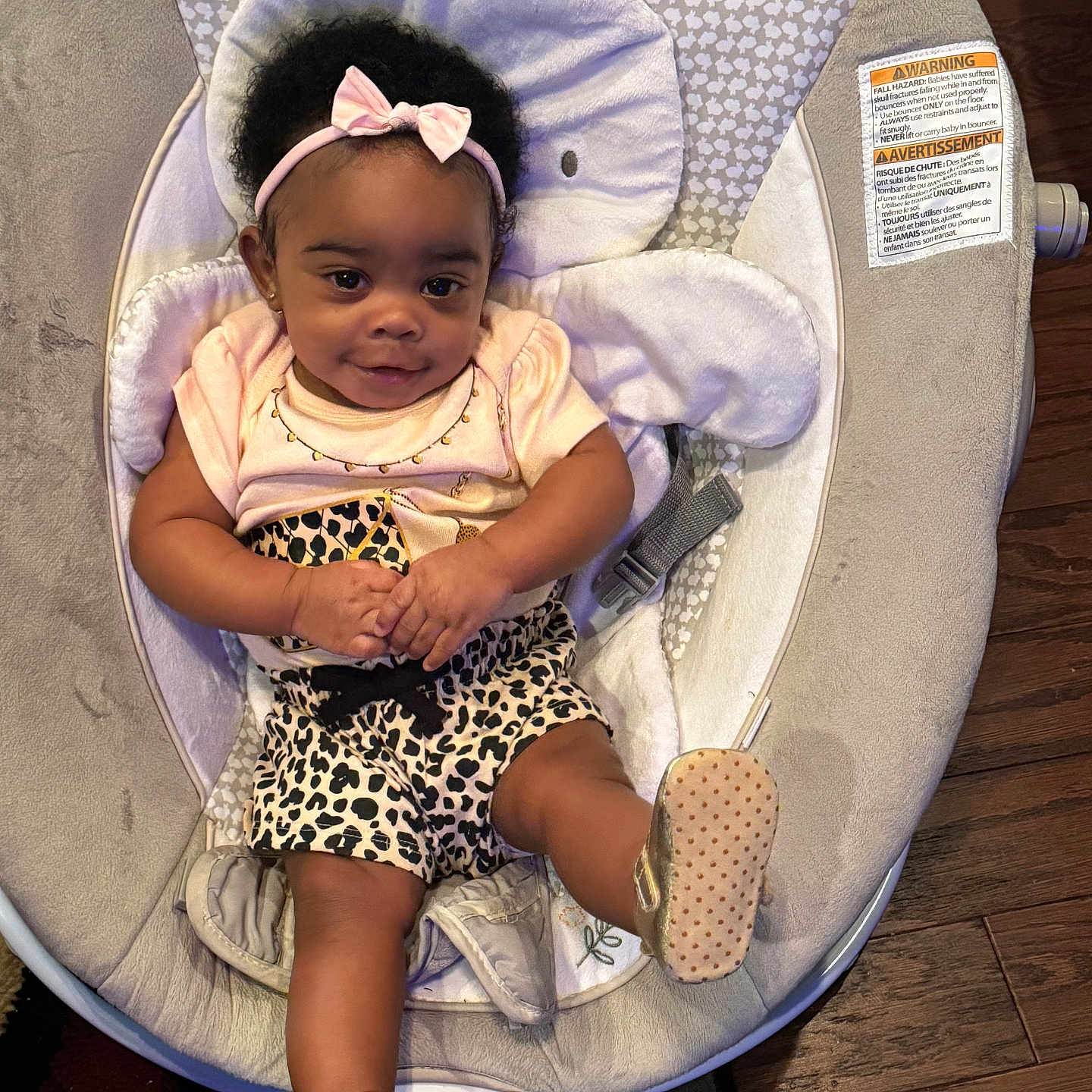 Mirakle is registered to the contest to win money with this photo: baby, baby_rocker, carpet, child, cute, elephant_design, footwear, gold_shoes, happy, headband, indoor, infant, leopard_print, person, pink_bow, portrait, shirt, shorts, smiling, wooden_floor