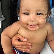 Joseph joined the competition — help win amazing prizes! baby, child, smile, face, hand, skin, hair, cute, infant, swimwear, red_shorts, blue_shorts, holding, person, portrait, closeup, happy, sitting, indoors, young