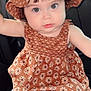 baby, child, car_seat, hat, dress, patterned_clothing, cute, infant, face, eyes, chubby_cheeks, sitting, indoors, portrait, person, headwear, clothing, seat, young_child, adorable