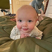 Sawyer is registered to the contest to win money with this photo: baby, infant, smile, face, eyes, plush_toy, elephant, blanket, bedroom, indoors, cute, child, person, soft_toy, lying_down, rosy_cheeks, clothing, warm, cozy, expression