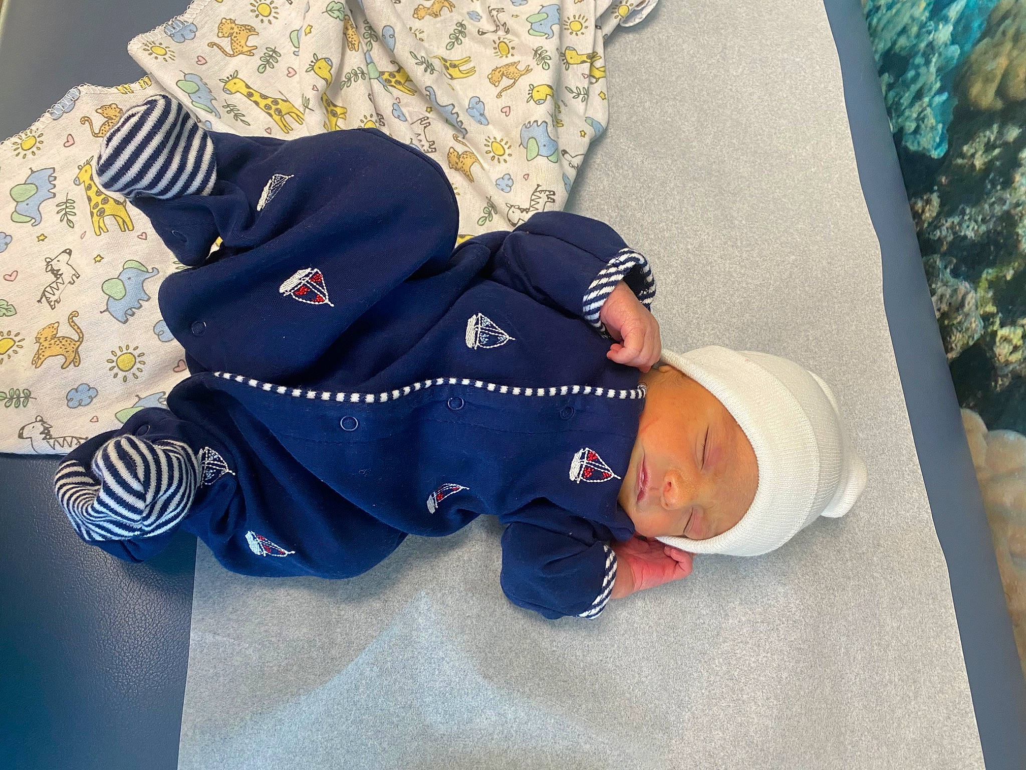 Nickolas is registered to the contest to win money with this photo: baby, baby_products, baby_sleeping, baby_toddler_clothing, carmine, child, comfort, electric_blue, fashion_accessory, font, hat, headgear, headwear, lap, linens, pattern, person, room, sitting, sleeve
