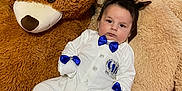Niță Damian a rejoint le concours — aidez-le/la à gagner de superbes lots ! baby, blue_bow, child, comfort, cozy, cute, decor, fabric, footwear, furniture, indoor, patterned_bedspread, plush_toy, portrait, seated, smiling, soft_toys, teddy_bear, toy, white_outfit