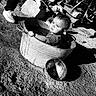 Theodore is registered to the contest to win money with this photo: baby, child, metal_tub, water, outdoor, dirt, person, legs, shoes, black_and_white, sunlight, shadow, hand, rustic, contemplative, candid, texture, footwear, rock, lid