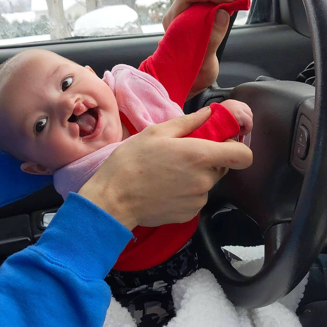 Mia participe au concours pour gagner de l'argent avec cette photo : automotive_mirror, automotive_window_part, baby, baby_toddler_clothing, car_seat, car_seat_cover, carmine, child, door, finger, head_restraint, motor_vehicle, person, rear_view_mirror, snow, steering_part, steering_wheel, thumb, toddler, tooth