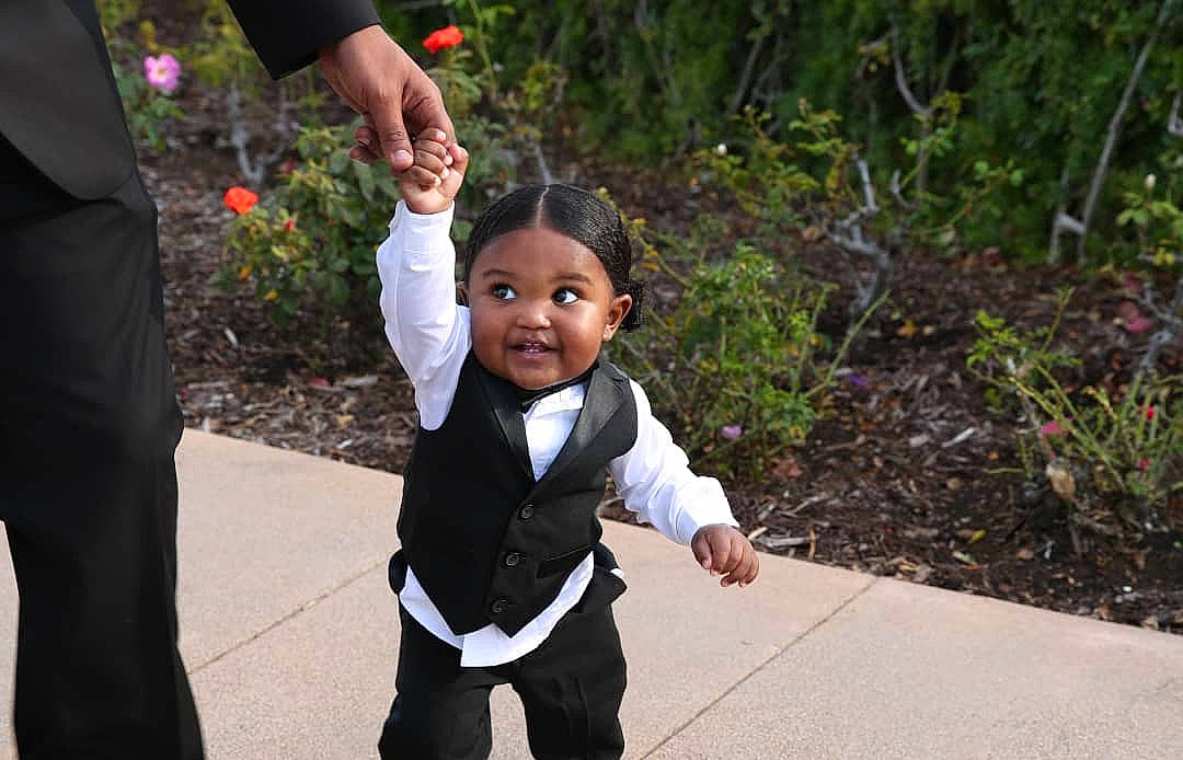 Asa is registered to the contest to win money with this photo: baby, bow_tie, ceremony, event, formal_wear, fun, gesture, grass, happy, leaf, leisure, people_in_nature, person, plant, recreation, rose_family, smile, suit, toddler, tradition