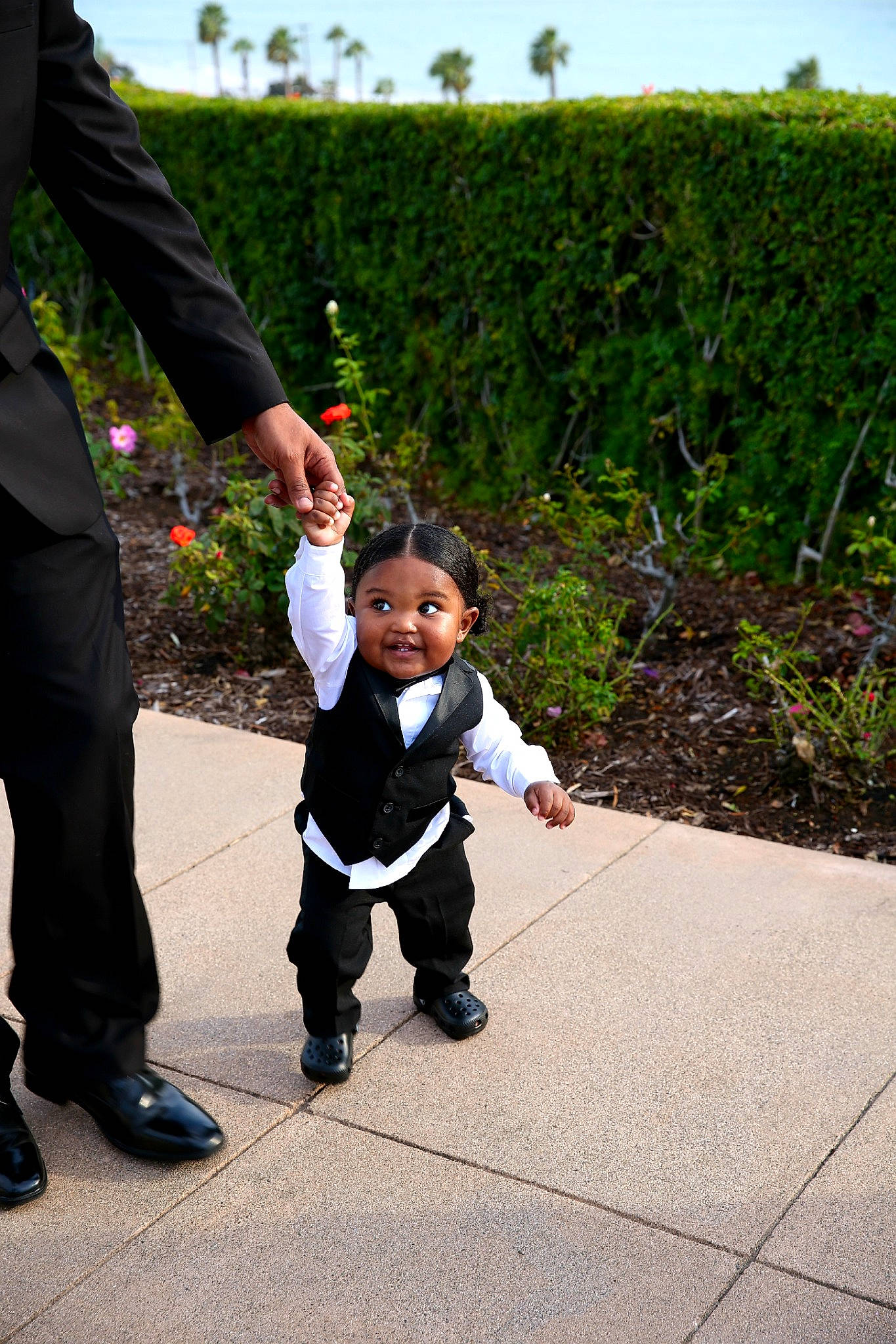 Asa is registered to the contest to win money with this photo: child, event, flooring, formal_wear, fun, gesture, grass, happy, holding_hands, leisure, people_in_nature, person, plant, shoe, sky, smile, sneakers, suit, toddler, tuxedo