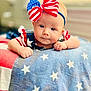 Remi joined the competition — help win amazing prizes! baby, infant, child, headband, bow, red, white, blue, stars, stripes, blanket, patriotic, clothing, face, portrait, cute, indoors, person, closeup, smiling