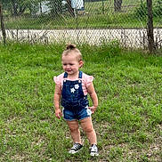 Arington joined the competition — help win amazing prizes! child, toddler, grass, outdoor, fence, denim_overalls, pink_shirt, shorts, sneakers, top_knot, trees, nature, person, summer, daylight, greenery, casual_clothing, standing, cute, young_child