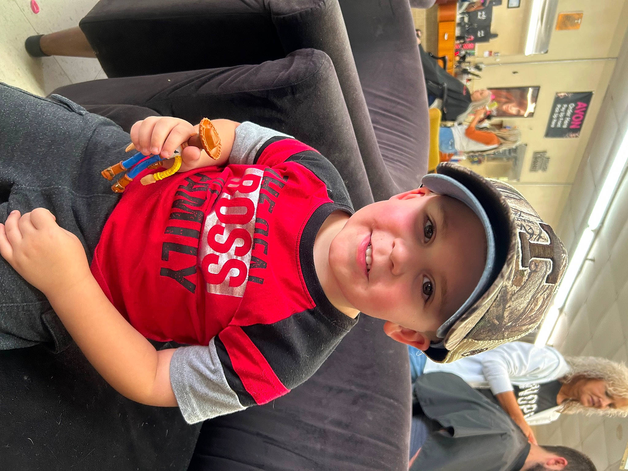 Jordan is registered to the contest to win money with this photo: blurred, car_seat, child, comfort, elbow, fun, happy, hat, headwear, human_leg, joy, knee, leisure, passenger, person, room, sitting, smile, t_shirt, thigh