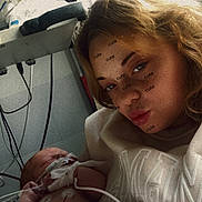 Maël a rejoint le concours — aidez-le/la à gagner de superbes lots ! newborn, baby, woman, hospital, medical_equipment, blanket, face, person, indoors, healthcare, patient, monitoring, cables, bed, young_adult, closeup, portrait, parent, child, hospital_room