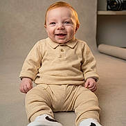 Maël participe au concours pour gagner de l'argent avec cette photo : baby, beige_outfit, camera, collar, cozy, cute, eyes, face, floor, hands, infant, neutral_background, portrait, red_hair, sitting, smile, smiling, studio, white_sneakers, young_child