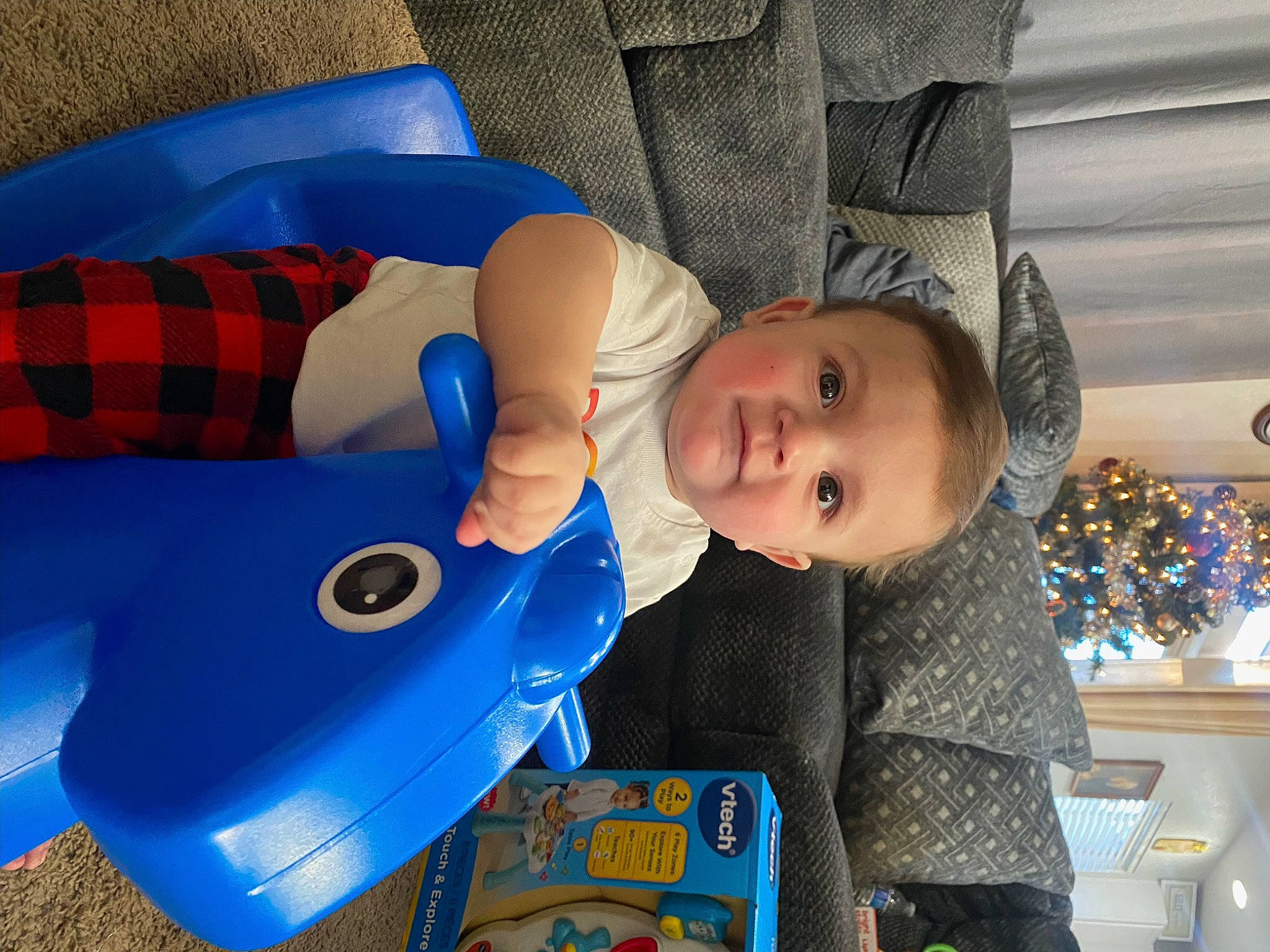 Christopher is registered to the contest to win money with this photo: baby, baby_products, baby_safety, baby_toddler_clothing, baby_toys, blue, child, comfort, electric_blue, fun, pattern, person, plaid, play, recreation, room, sitting, sleeve, tartan, toddler
