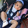 baby, infant, stroller, car_seat, bottle, headband, flower, white_shoes, outdoor, brick_floor, curious, straps, cute, child, person, portrait, clothing, seat, footwear, baby_girl