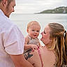 baby, child, parents, family, smiling, happy, portrait, outdoor, seaside, beach, ocean, water, coastline, hillside, island, man, woman, holding, tattoo, summer