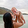 baby, child, parent, outdoor, lakeside, water, hills, landscape, family, portrait, smiling, happy, infant, holding, lifting, arms, dress, romper, nature, sky